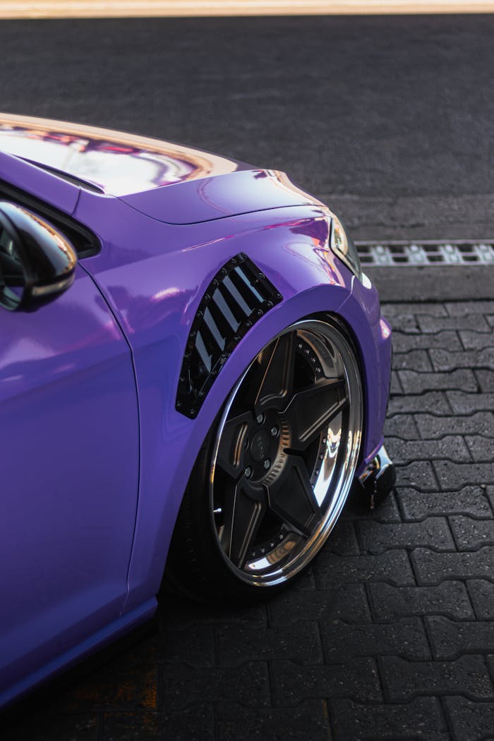 Close-up view of a purple cars front wheel showcasing sleek design and vibrant color.